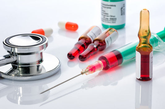 A close-up of medical supplies, including a syringe filled with red liquid.