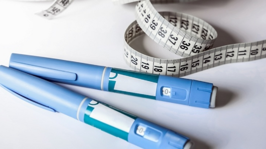wo blue medical injection pens placed on a white surface with a coiled measuring tape for weight management